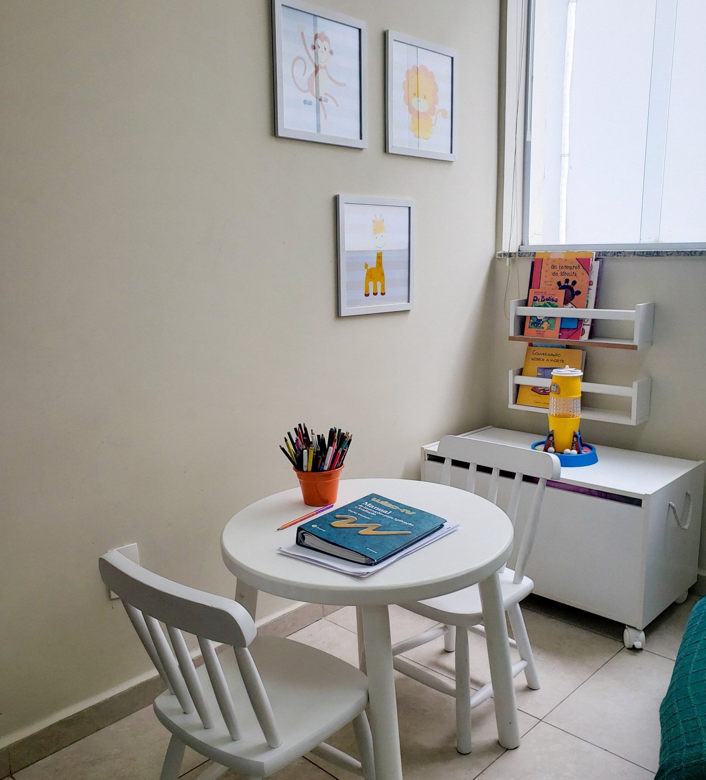 Sala de atendimento infantil com mesinha, cadeiras e livros